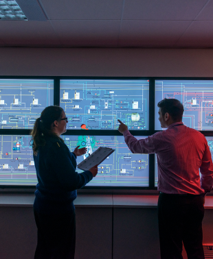 Tutor and student in front of monitors in ship's engine room simulator