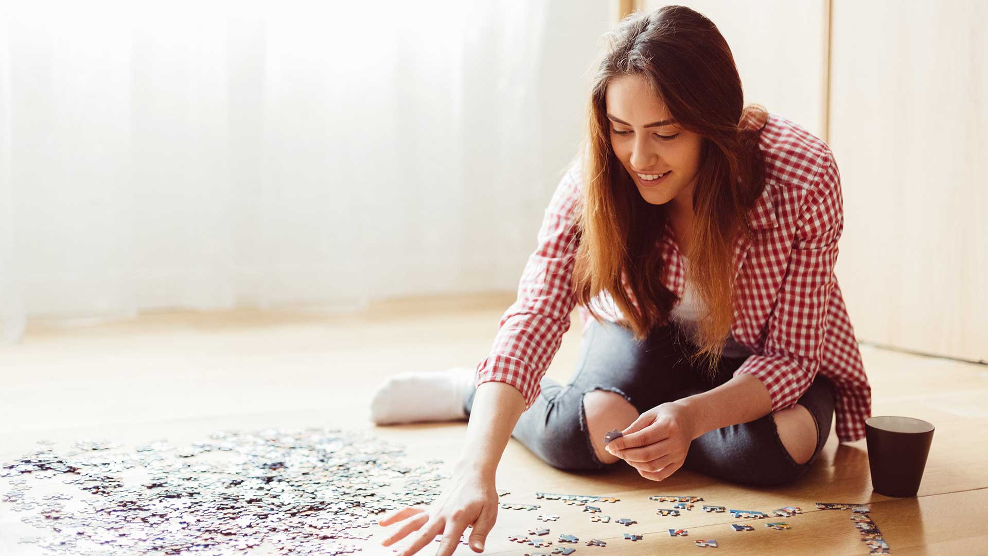 Frau setzt auf dem Fußboden ein Puzzle zusammen