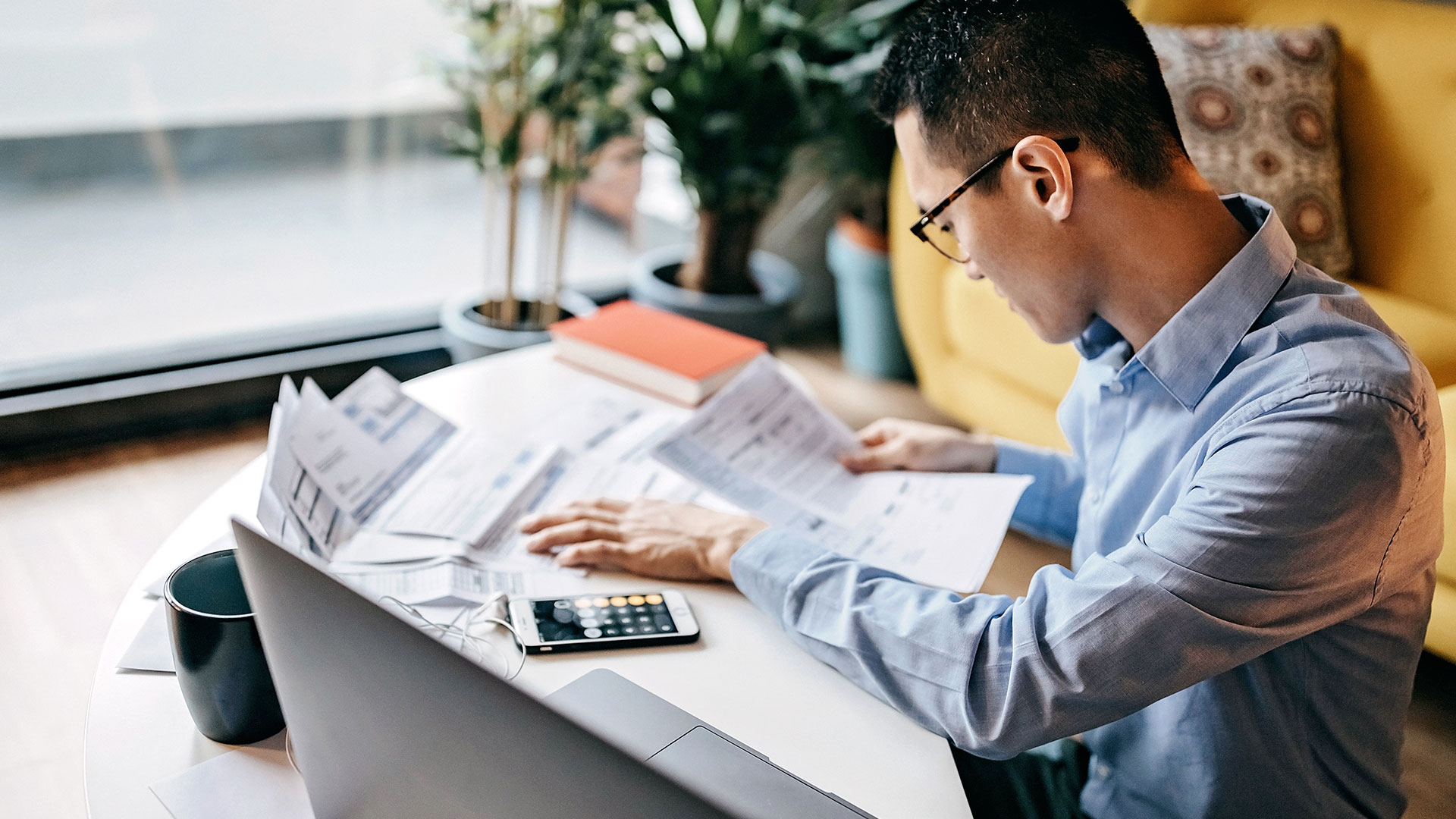 Prüfung von Unterlagen mit Taschenrechner an einem Schreibtisch