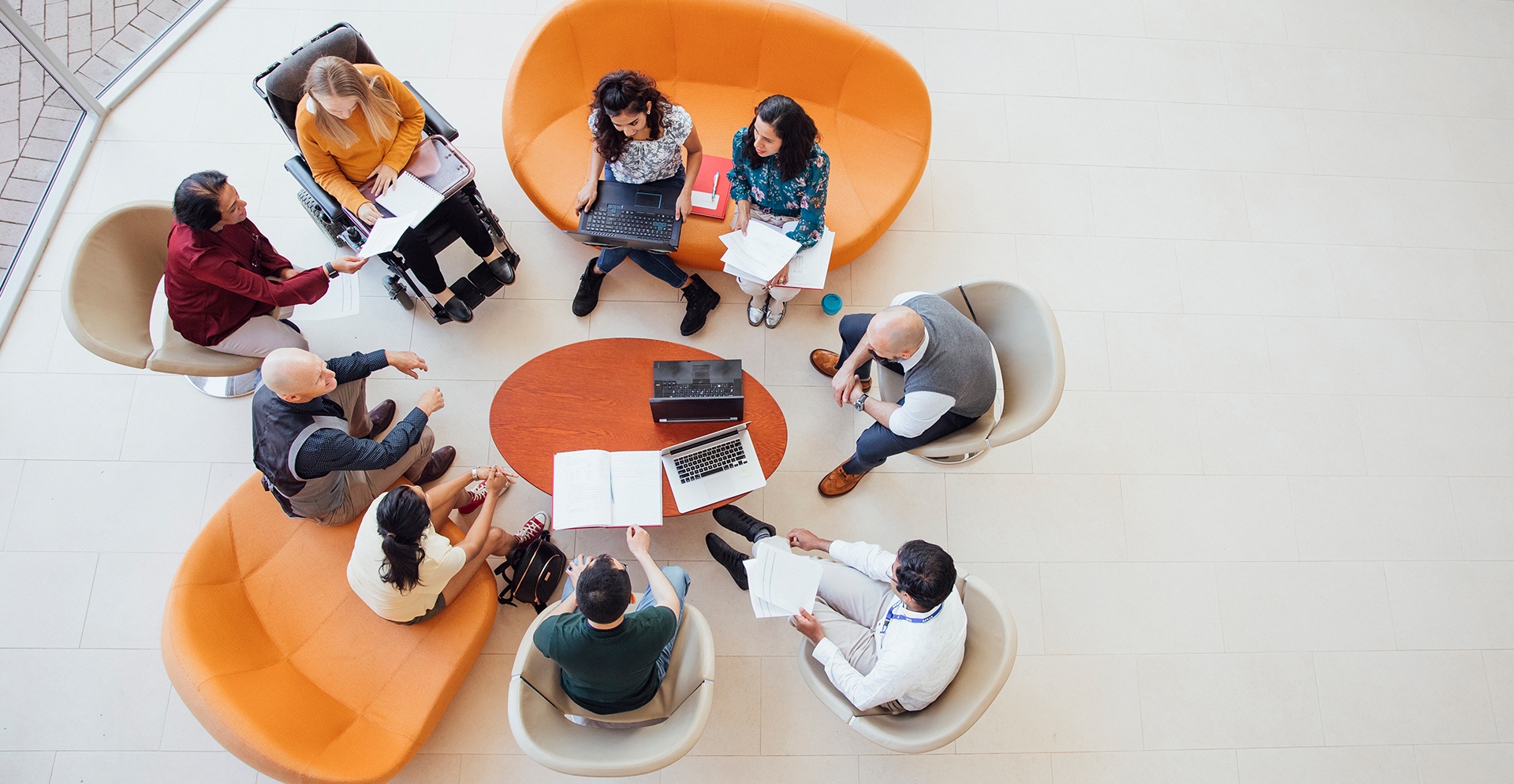 Groep collega's vanaf boven bekeken die zittend vergaderen rondom een tafeltje 