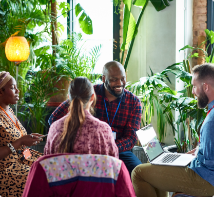 A diverse group of individuals sitting around a table, engrossed in their work on laptops.