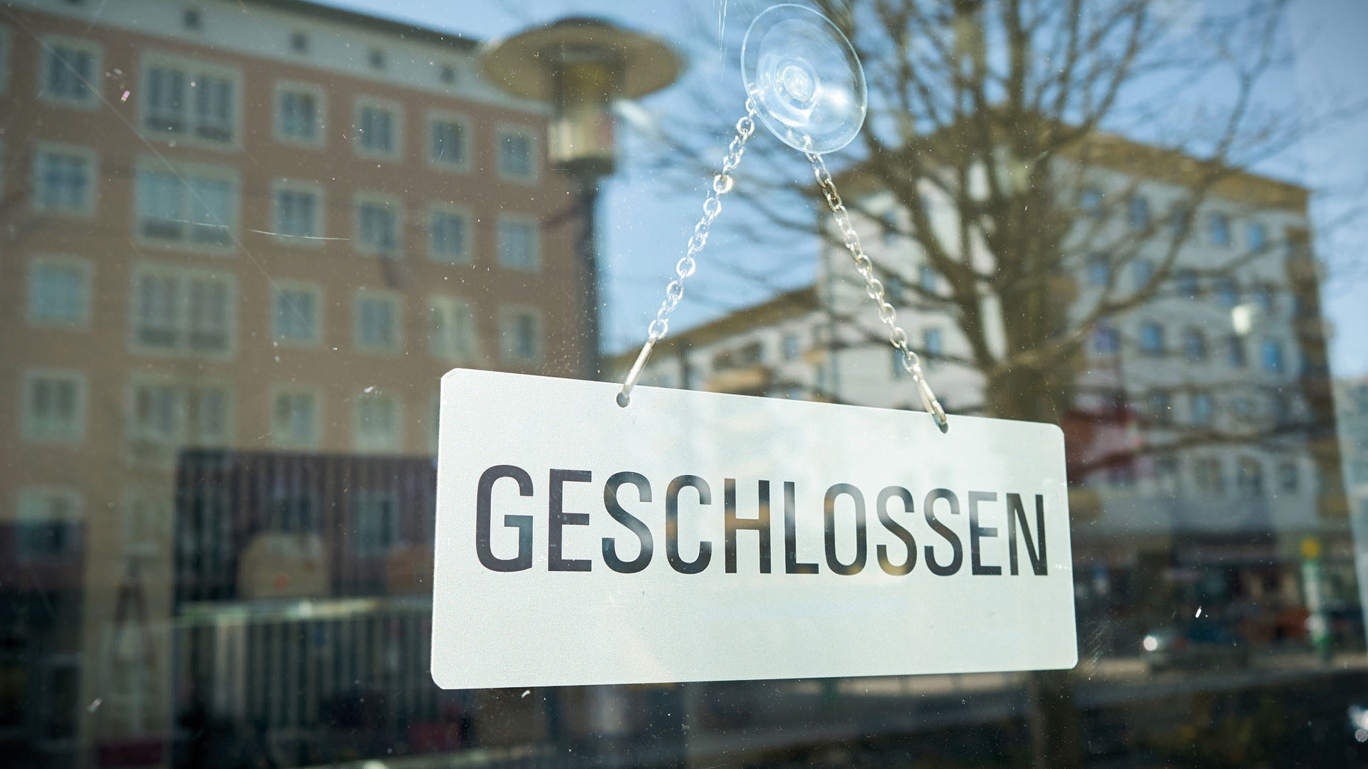 Schild mit der Aufschrift "Geschlossen" hinter einer Glasscheibe