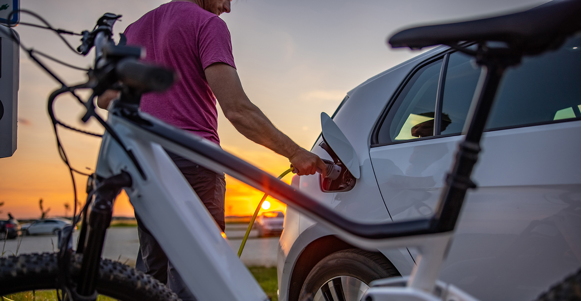 Mann steckt elektrischen Stecker in Auto zum Aufladen