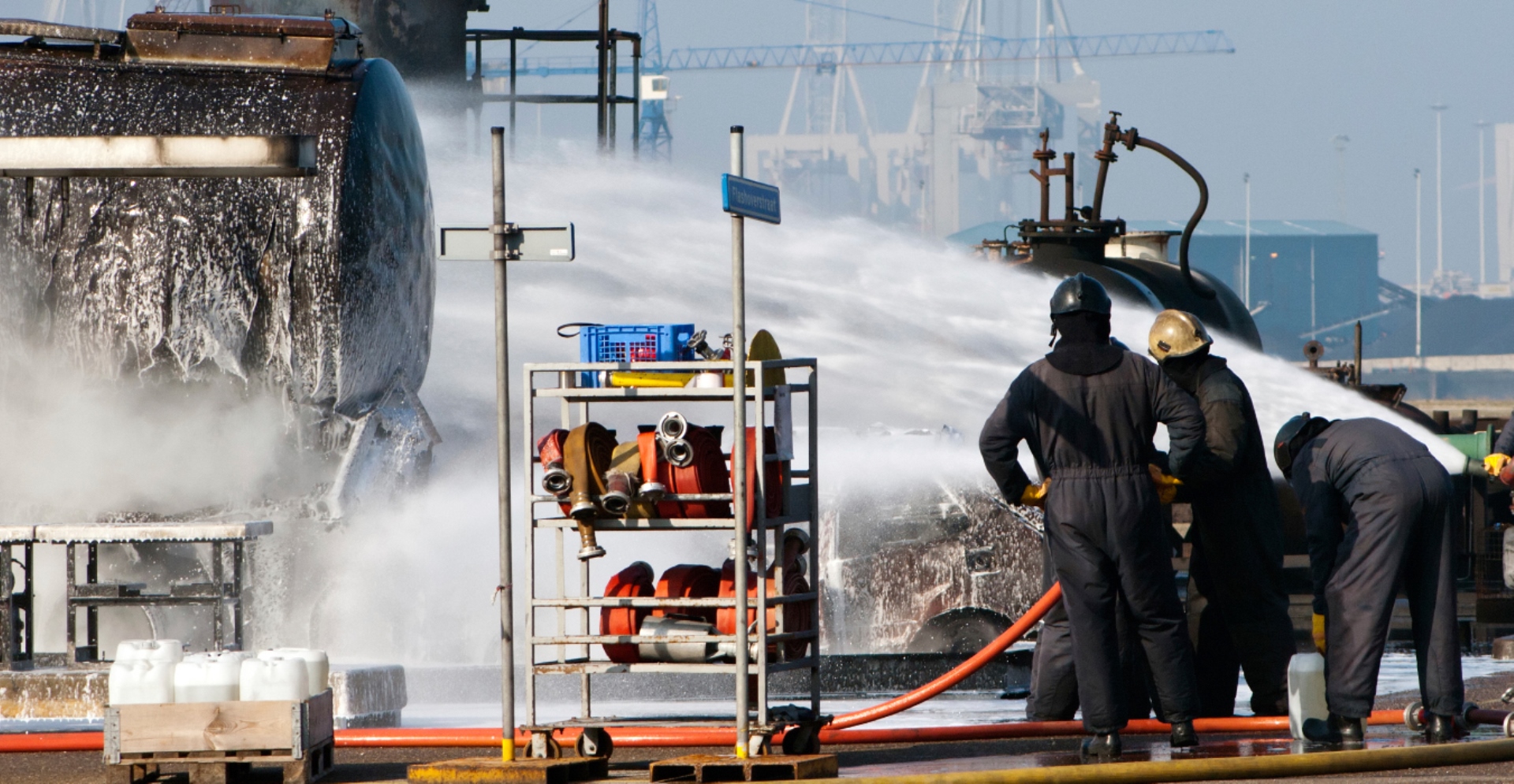 Brandweermannen blussen zwarte tankwagen met schuim