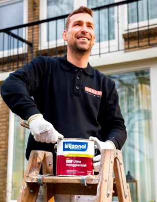 Schilder op een trap bezig om een blik Wijzonol te openen om aan het werk te gaan.